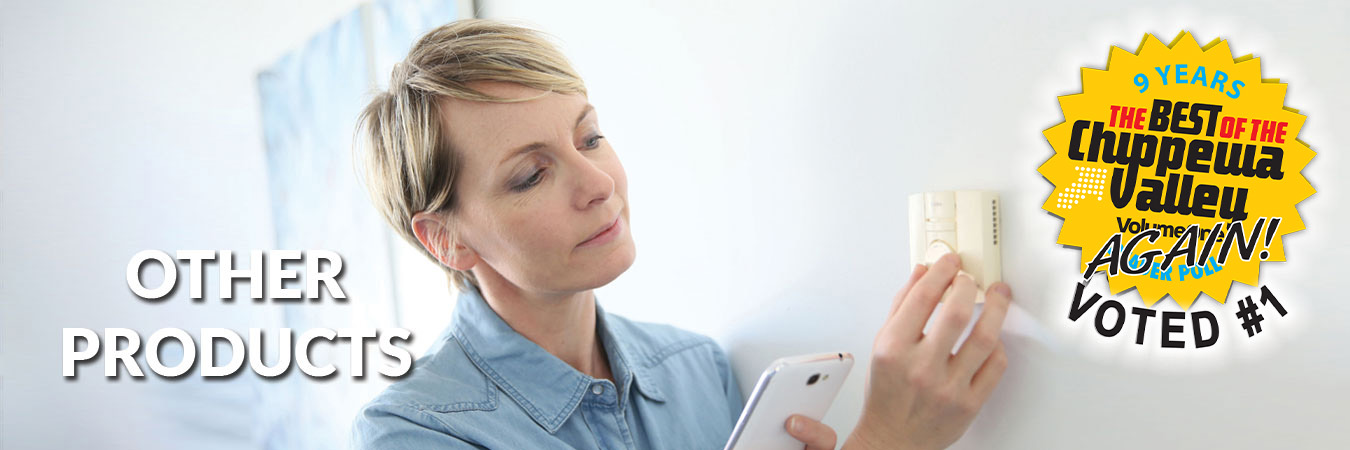 photo of smiling woman sitting on a couch with a remote control in her hand that controls the air-conditioning unit