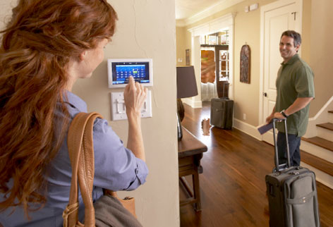 photo of a woman adjusting the temperature on a thermostat